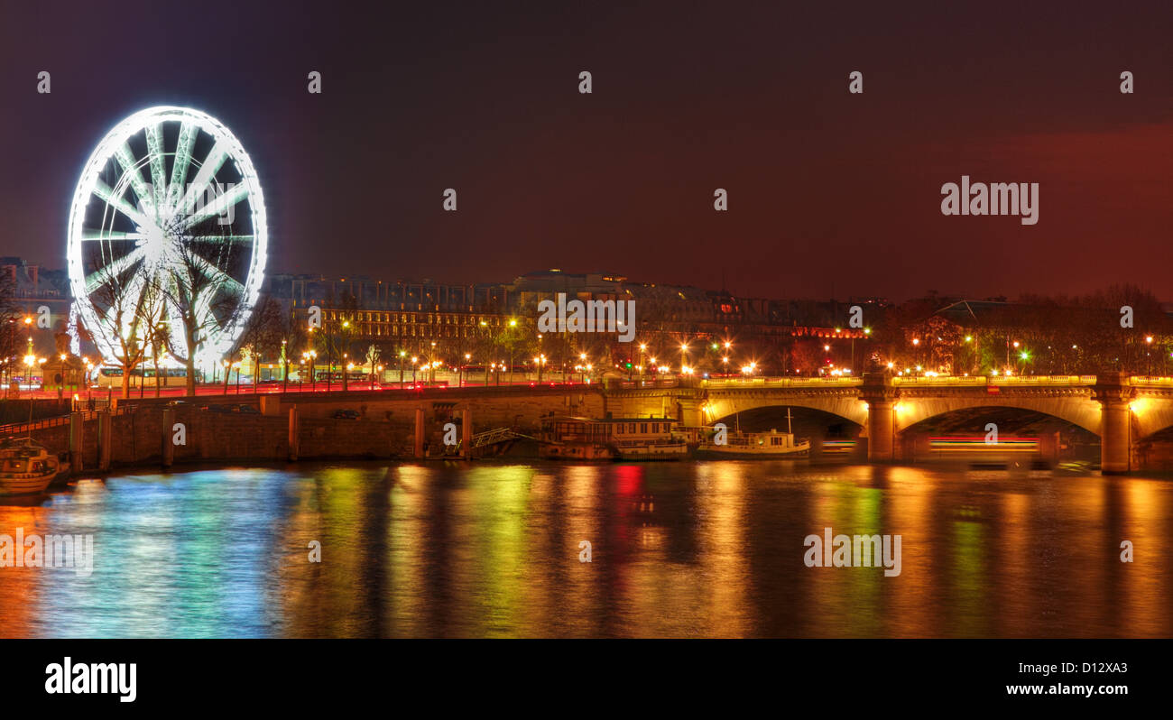 Immagine del traghetto illuminato volante situato in Place de la Concorde e colorati riflessi di luce nel fiume Senna a Parigi. Foto Stock