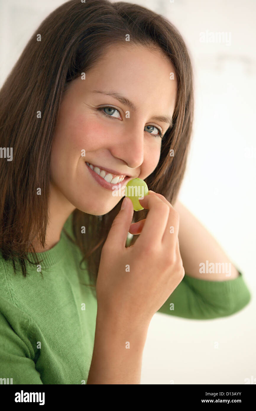 In Germania, in Baviera, Monaco di Baviera, giovane donna mangiare uva, sorridente, ritratto Foto Stock