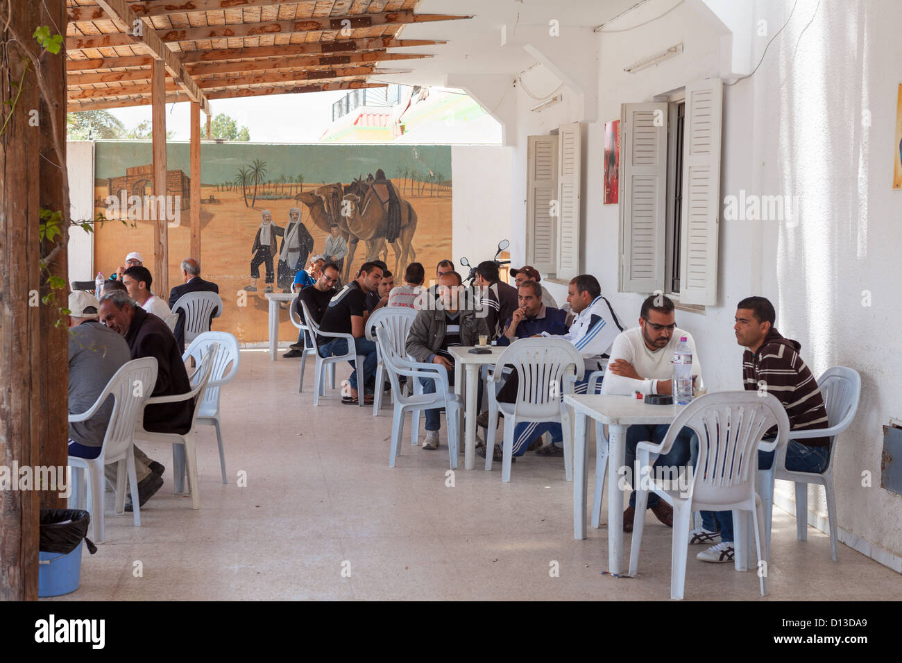 La popolazione maschile è seduta in corrispondenza di un bordo strada cafe durante la siesta, Tunisia, Africa Foto Stock