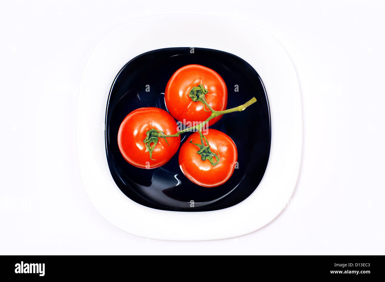 Mazzetto di tre pomodoro sul nero e le piastre bianche Foto Stock