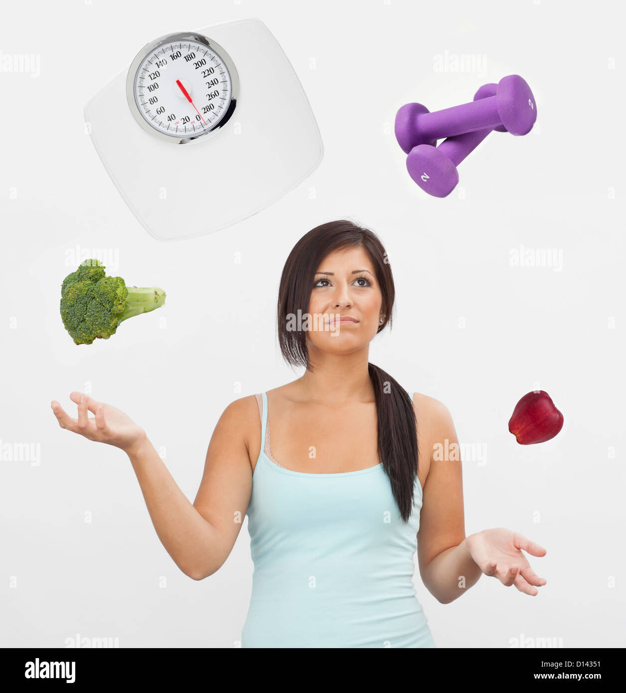 Studio shot della giovane donna giocoleria con bilancia, pesi, frutta e verdura Foto Stock