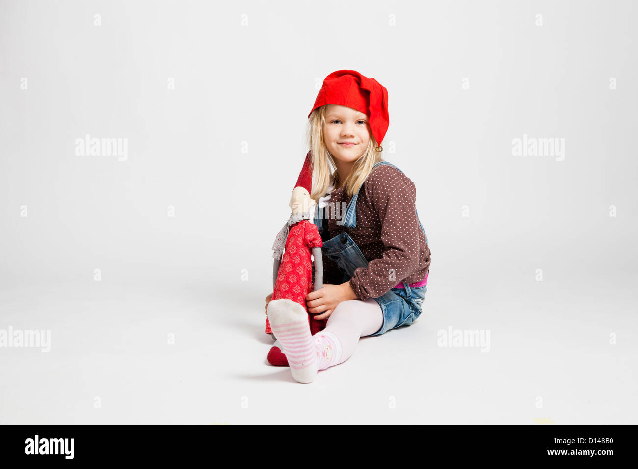 Ritratto in studio di Felice sorridente ragazza giovane azienda elf natale bambola mentre è seduto Foto Stock