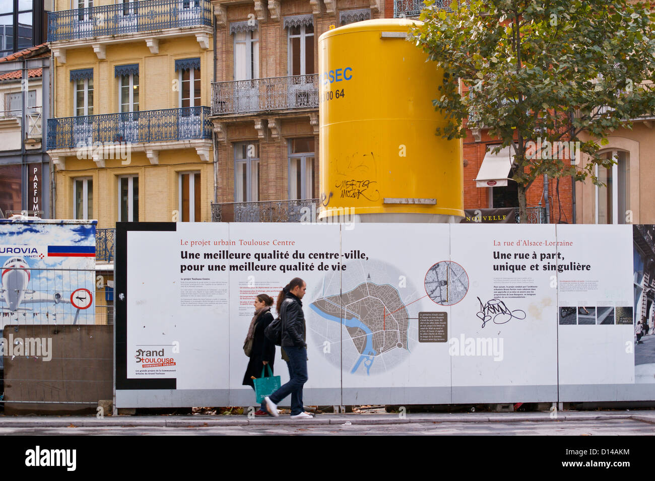 Un uomo e una donna passando per la strada di fronte a una riqualificazione urbana information board, Toulouse, Haute-Garonne, Francia Foto Stock