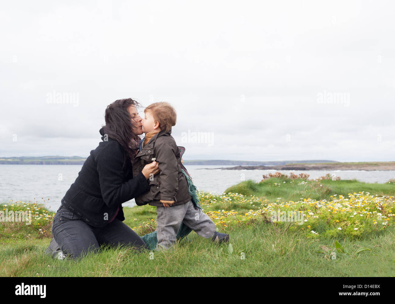 Madre e figlio baciare in campo erboso Foto Stock