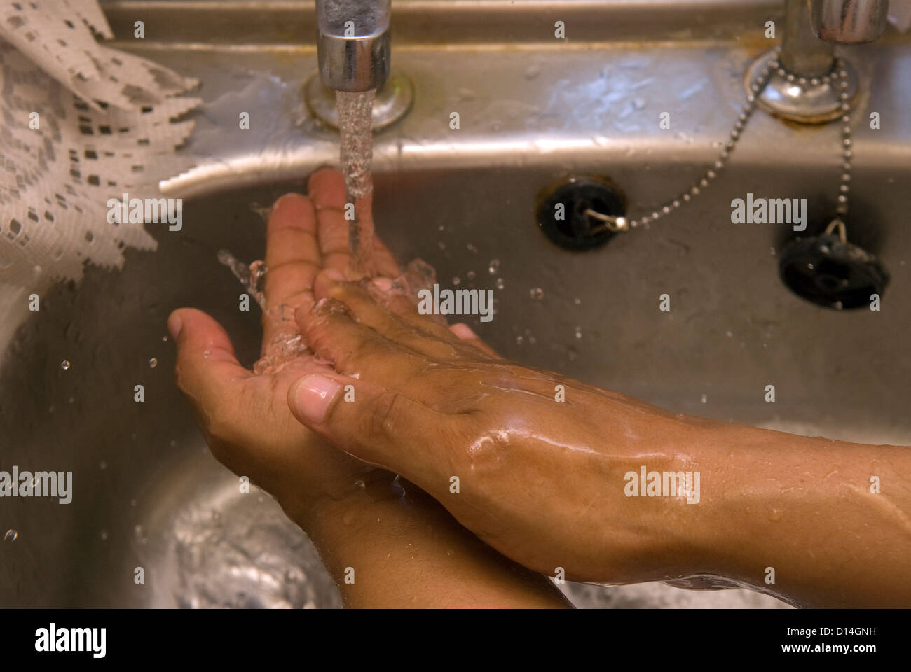 L'uomo lavarsi le mani in cucina sotto il rubinetto, Londra, Regno Unito. Il modello rilasciato l'immagine. Foto Stock