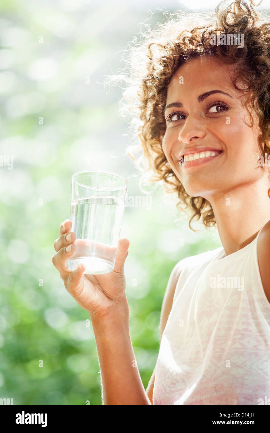 Donna sorridente di bere un bicchiere di acqua Foto Stock