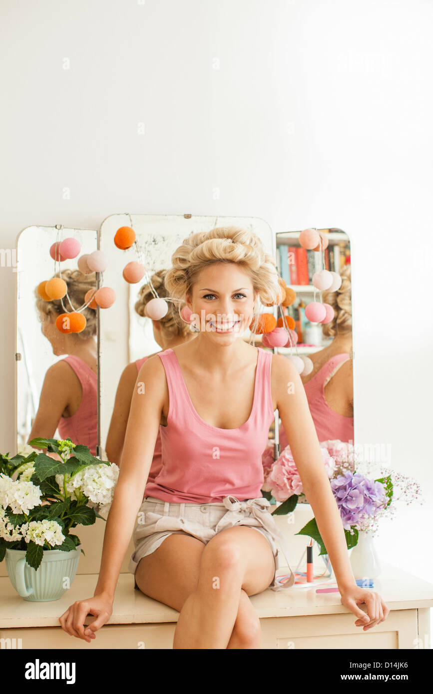 Donna sorridente seduto sulla vanità Foto Stock
