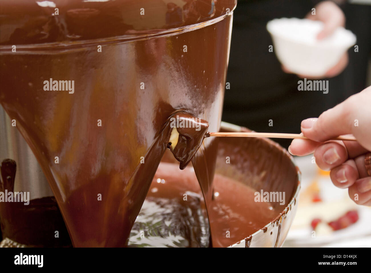 Fetta di ananas che è appena stata appena immerso nel latte caldo la fonduta di cioccolato. Foto Stock