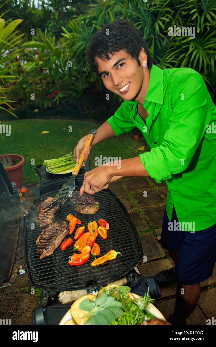 Hawaii, giovane prepara Barbecue esterno festa nel giardino delle Hawaii. Foto Stock