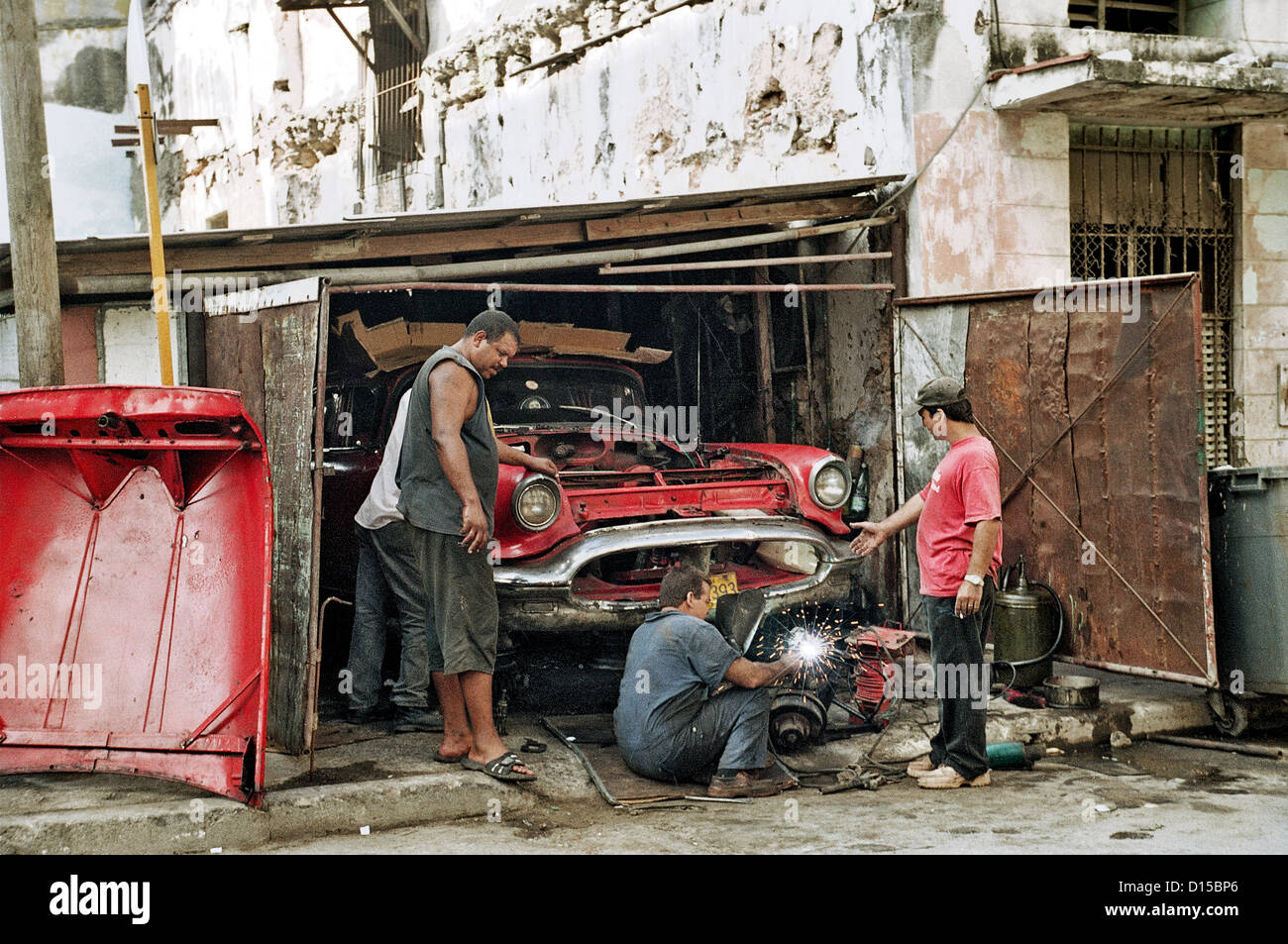 L'Avana, Cuba, padre tinkers con i suoi figli in un vecchio Chevrolet Foto Stock