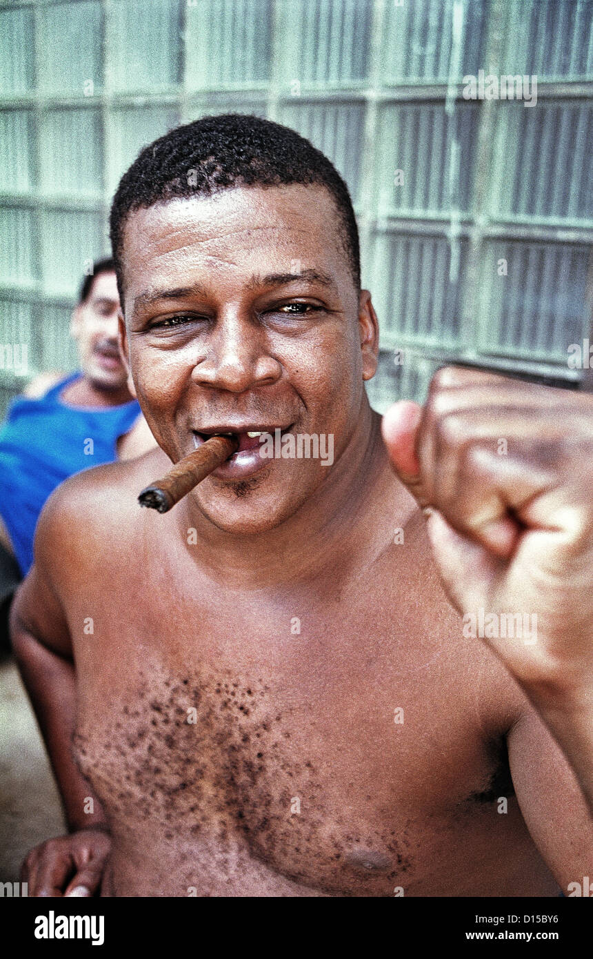 L'Avana, Cuba, uomo sorridente con una libera la parte superiore del corpo, un sigaro e un pugno chiuso Foto Stock