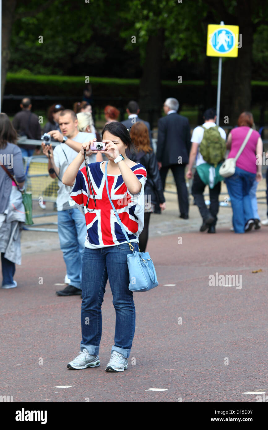 Turista femminile indossando Unione Jack T-shirt per fotografare in Pall Mall dopo Trooping il colore , Londra , Inghilterra Foto Stock