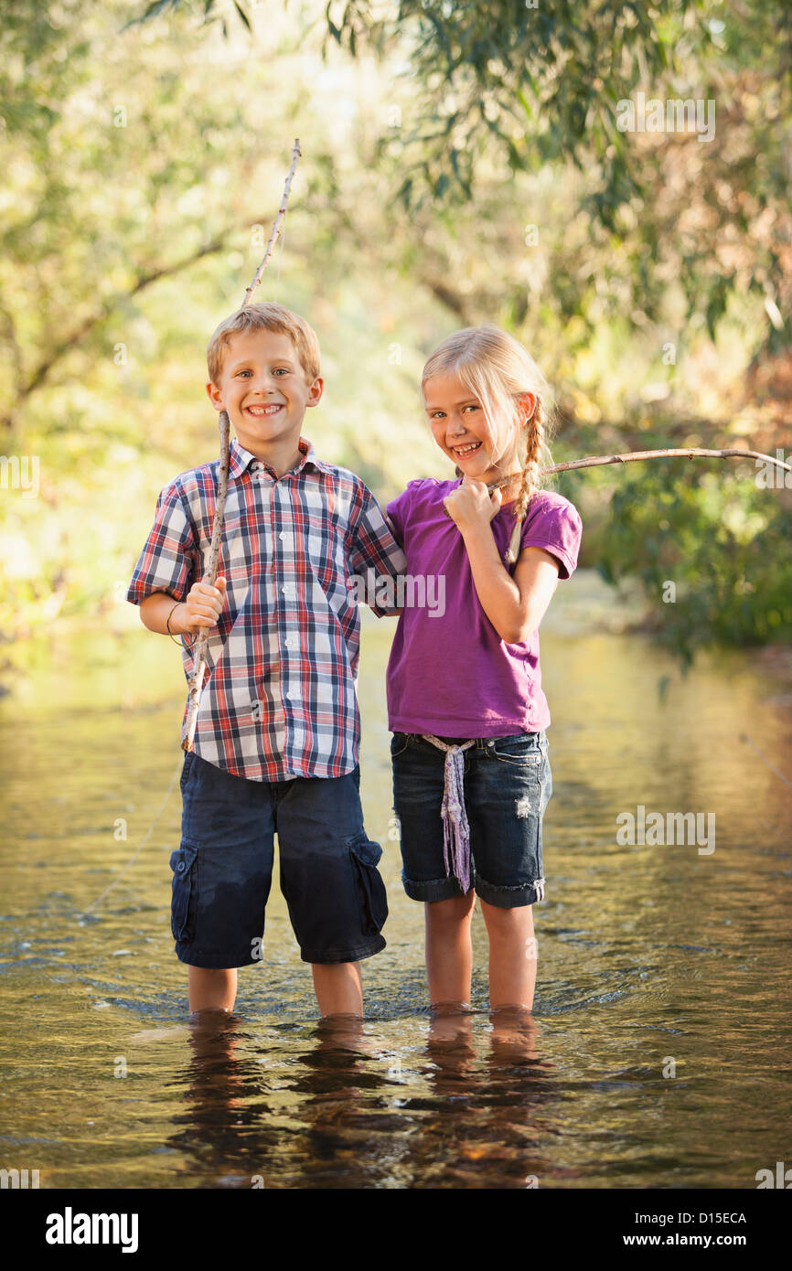 Stati Uniti d'America, Utah, Lehi, Little Boy (6-7) e bambina (4-5) in piedi insieme nella piccola azienda di vapore bastone di legno poli di pesca Foto Stock