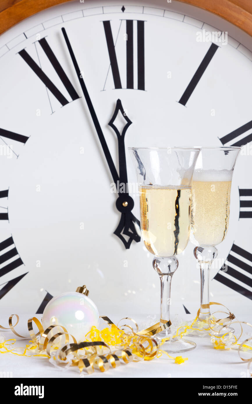 In procinto di colpire la mezzanotte di Capodanno con champagne e streamers davanti a un grande orologio. Foto Stock