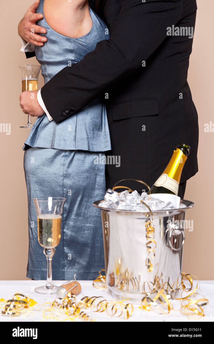 Un giovane che abbraccia con bicchieri di champagne in un party, buona immagine per il Veglione di Capodanno, matrimonio o anniversario temi. Foto Stock