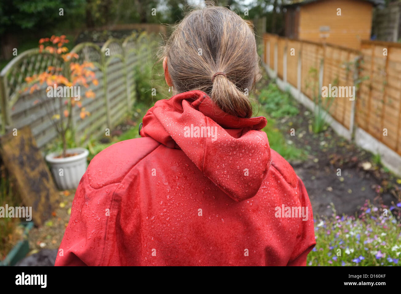 Giovane donna in una giacca a vento umido nel suo giardino sul retro a Stockport, Inghilterra Foto Stock