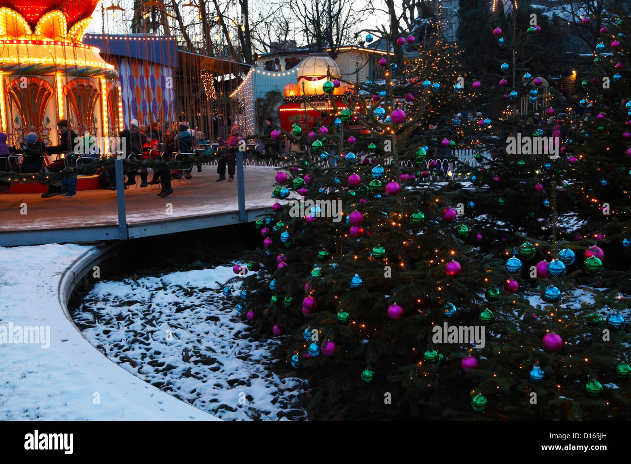 Merry-go-round, alberi di Natale e decorazioni a crepuscolo presso il mercato di Natale nella coperta di neve Tivoli, Copenhagen, Danimarca Foto Stock