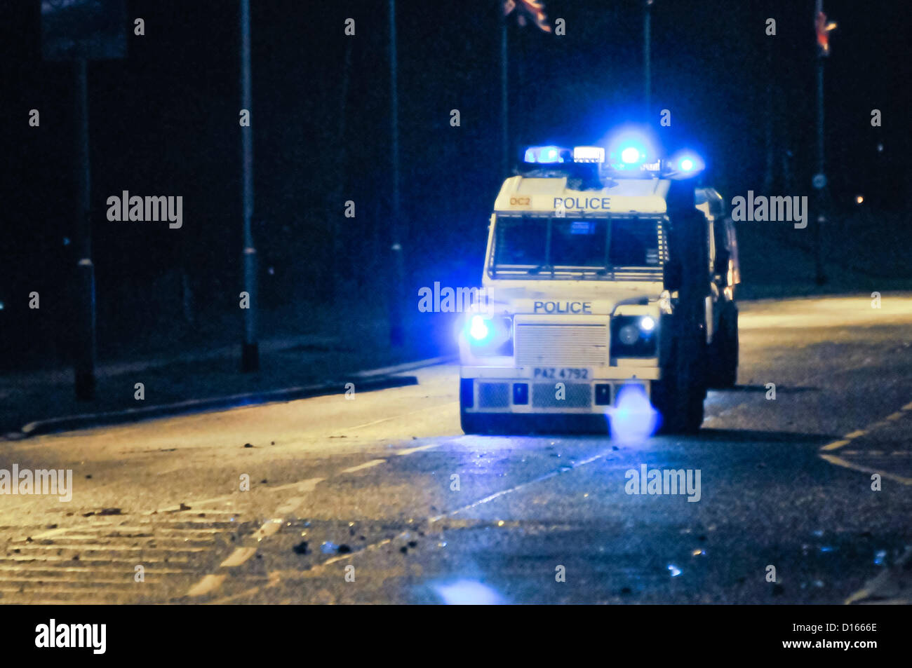 Due PSNI landrovers blindati viaggiano lungo una strada a velocità di notte, con le luci blu lampeggiante Foto Stock