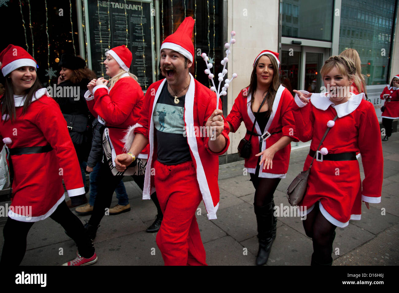 Londra, Regno Unito. Domenica 9 dicembre 2012. Un flash mob di Babbo Natale scende play per telecamera. Celebrato il Natale qui con l'annuale Santa Pub Crawl parte visitando i famosi pub & attrazioni di Londra con tutti decorati in rosso jolly Santa tute. Organizzato da fanatici, un australiano sport e società di partito. Alamy LIve News Foto Stock