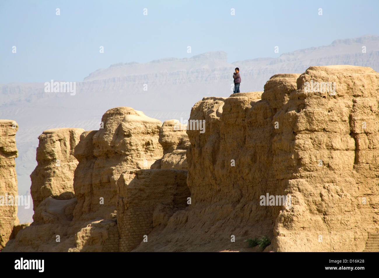 Un ragazzo si erge sulla cima delle rovine di antiche città Gaochang vicino a Turfan lungo la Silkroad, Uyghur Regione autonoma, Cina Foto Stock