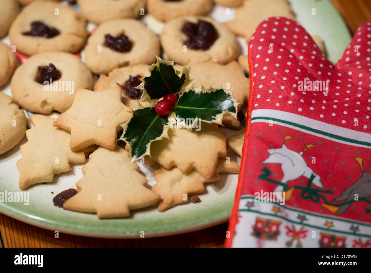 Biscotti di Natale sulla piastra con Ilex e guanti da forno Foto Stock