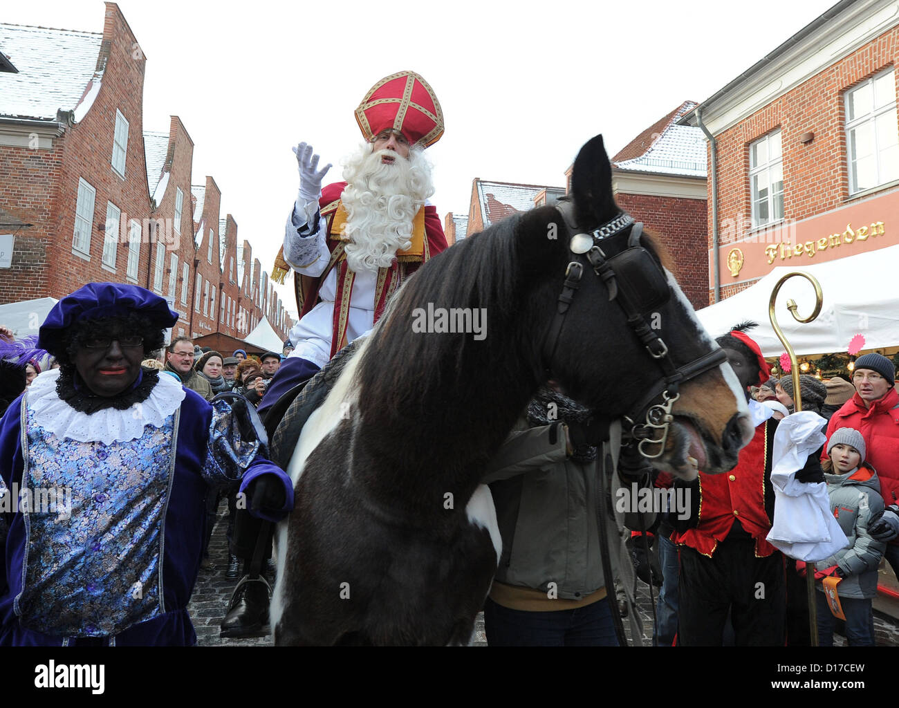 Un uomo vestito da Sinterklaas (Santa Clause) siede su un cavallo accompagnato da assistenti nel vestito in costume attraverso il cosiddetto Quartiere Olandese a Potsdam, in Germania, 8 dicembre 2012. L'Olandese tradizionale mercato di Natale si apre le sue porte per questo anno la stagione di Natale. Foto: Bernd Settnik Foto Stock