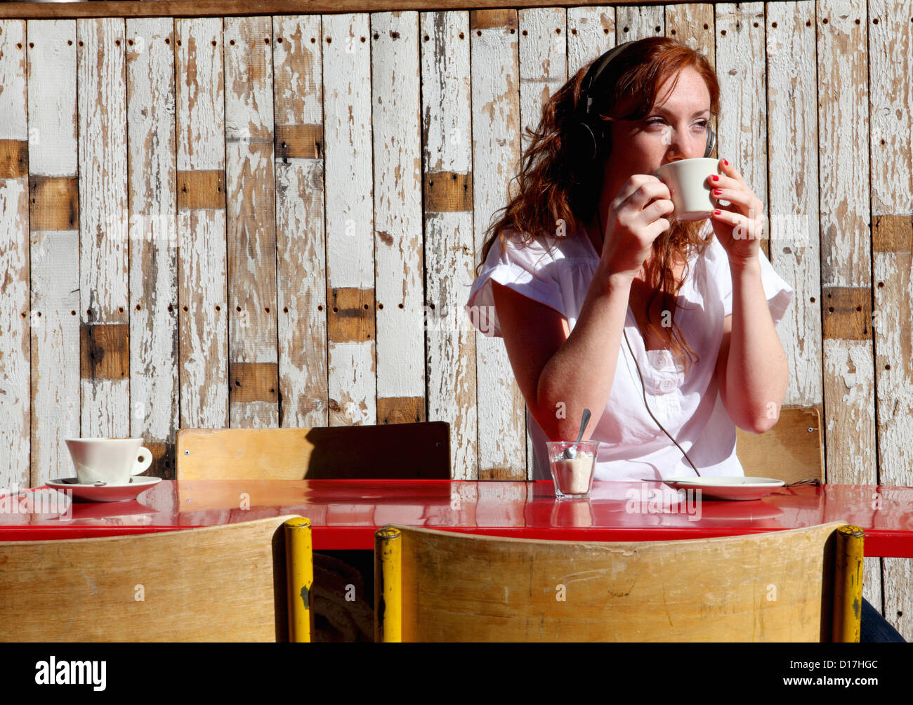 La donna nelle cuffie di bere il caffè Foto Stock