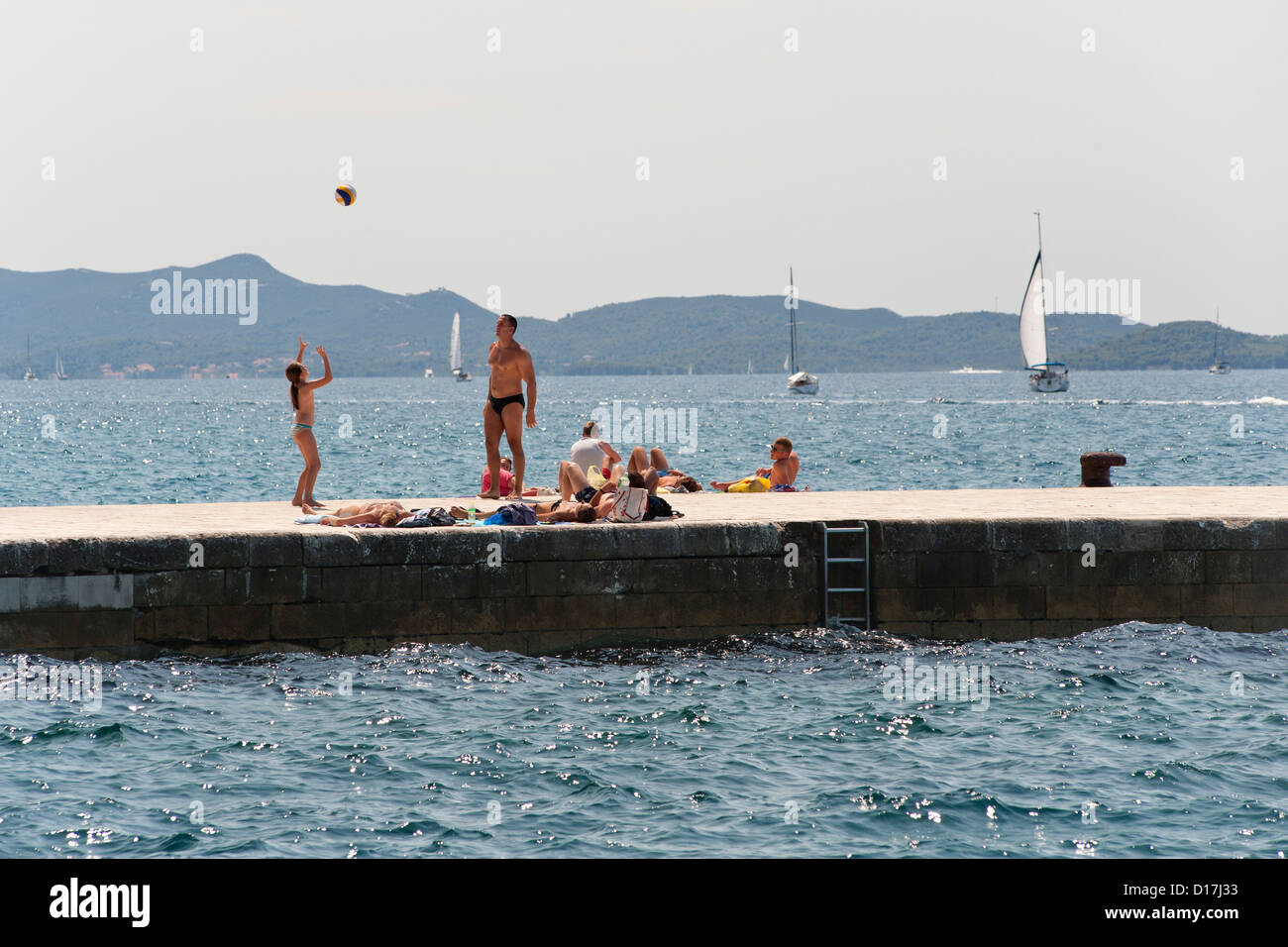 L uomo e la ragazza che gioca con una sfera su una struttura di frangionde in Zadar sulla costa adriatica della Croazia. Foto Stock