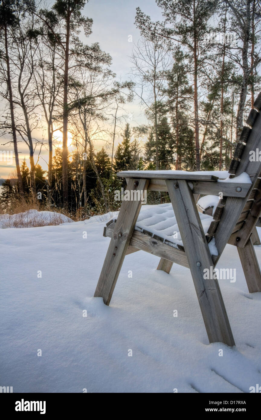 Sedia vuota ricoperta di neve, di fronte e di sera al tramonto e innevato paesaggio invernale Foto Stock