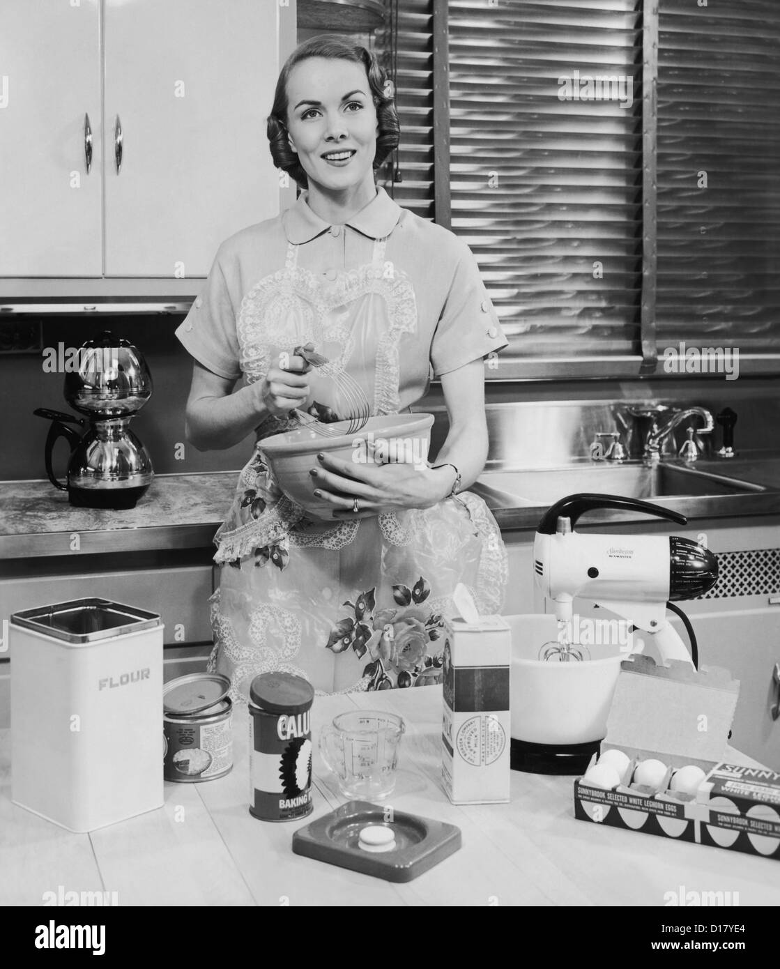 Donna con grembiule la cottura nella sua cucina Foto Stock