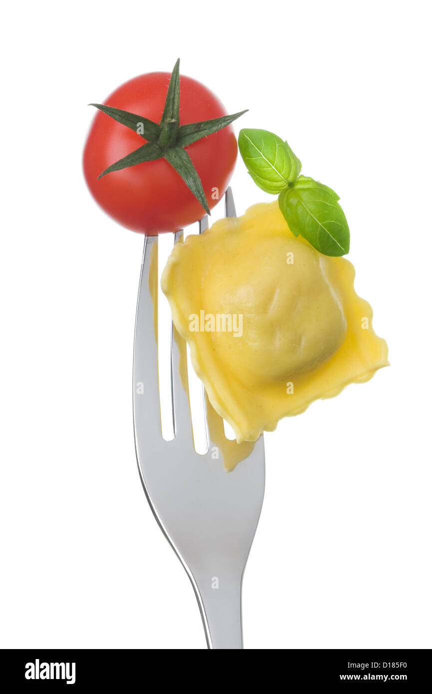 Ravioli di pasta di pomodoro e basilico su una forcella contro uno sfondo bianco Foto Stock