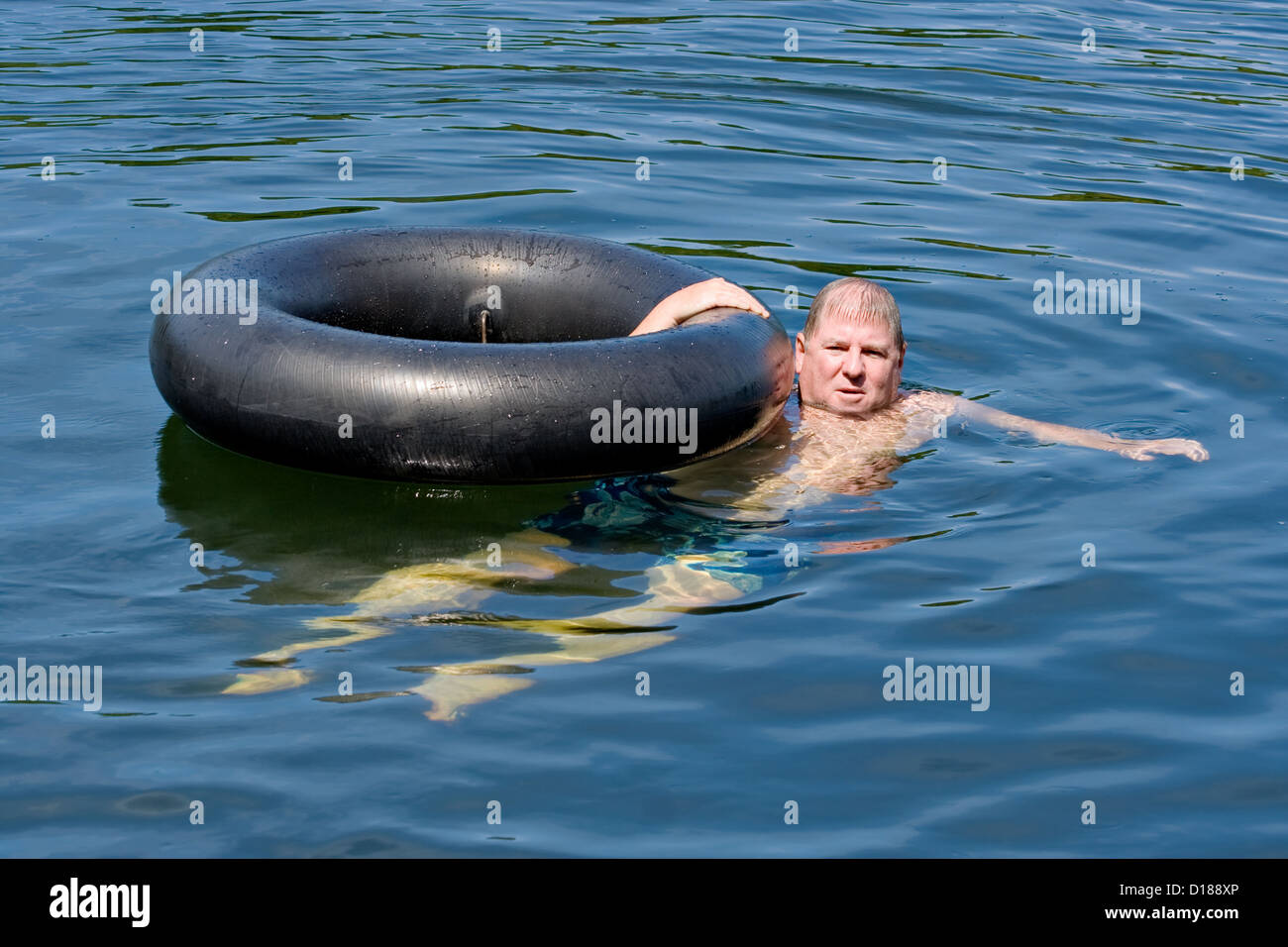 Un uomo in acqua flottante con un tubo interno Foto Stock