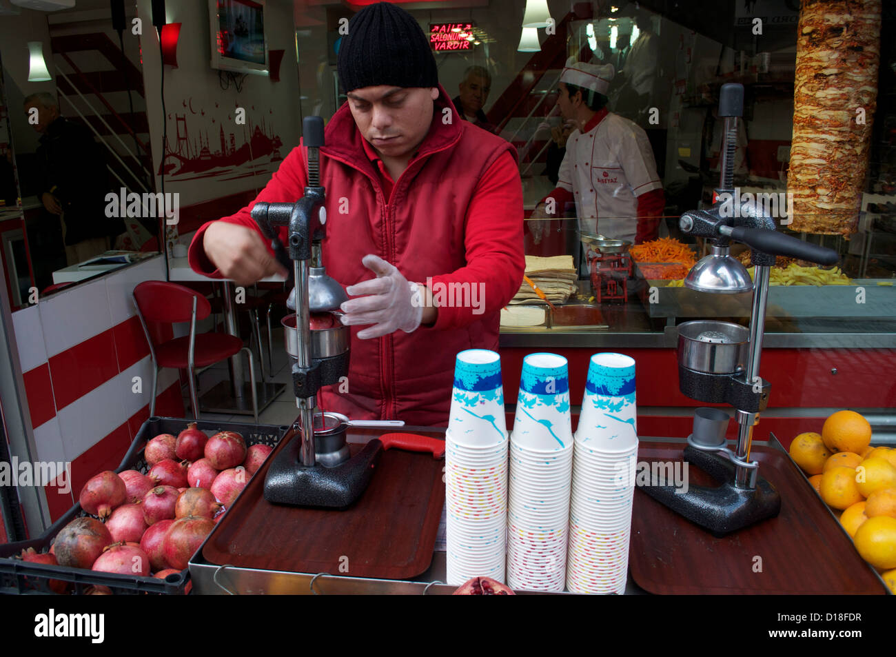 Il succo di melograno venditore in Istanbul Turchia utilizzando una melagrana premere Foto Stock