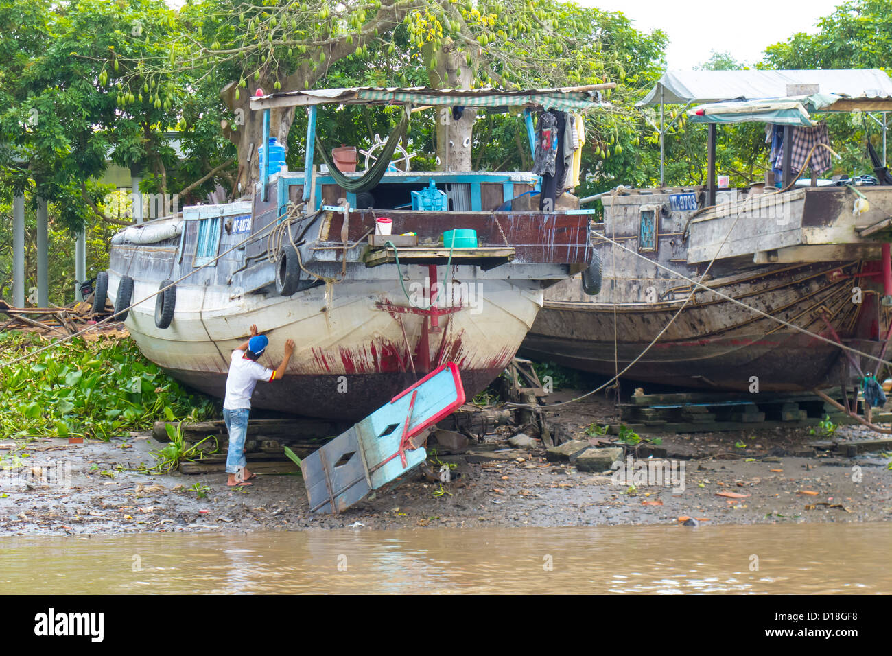Uomo di ispezionare lo scafo di una barca nella regione del Delta del Mekong del Vietnam Foto Stock