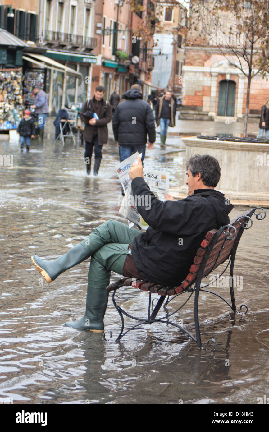 Uomo che legge il giornale durante l' "acqua alta" flood, Campo Santa Margherita, Venezia. Foto Stock