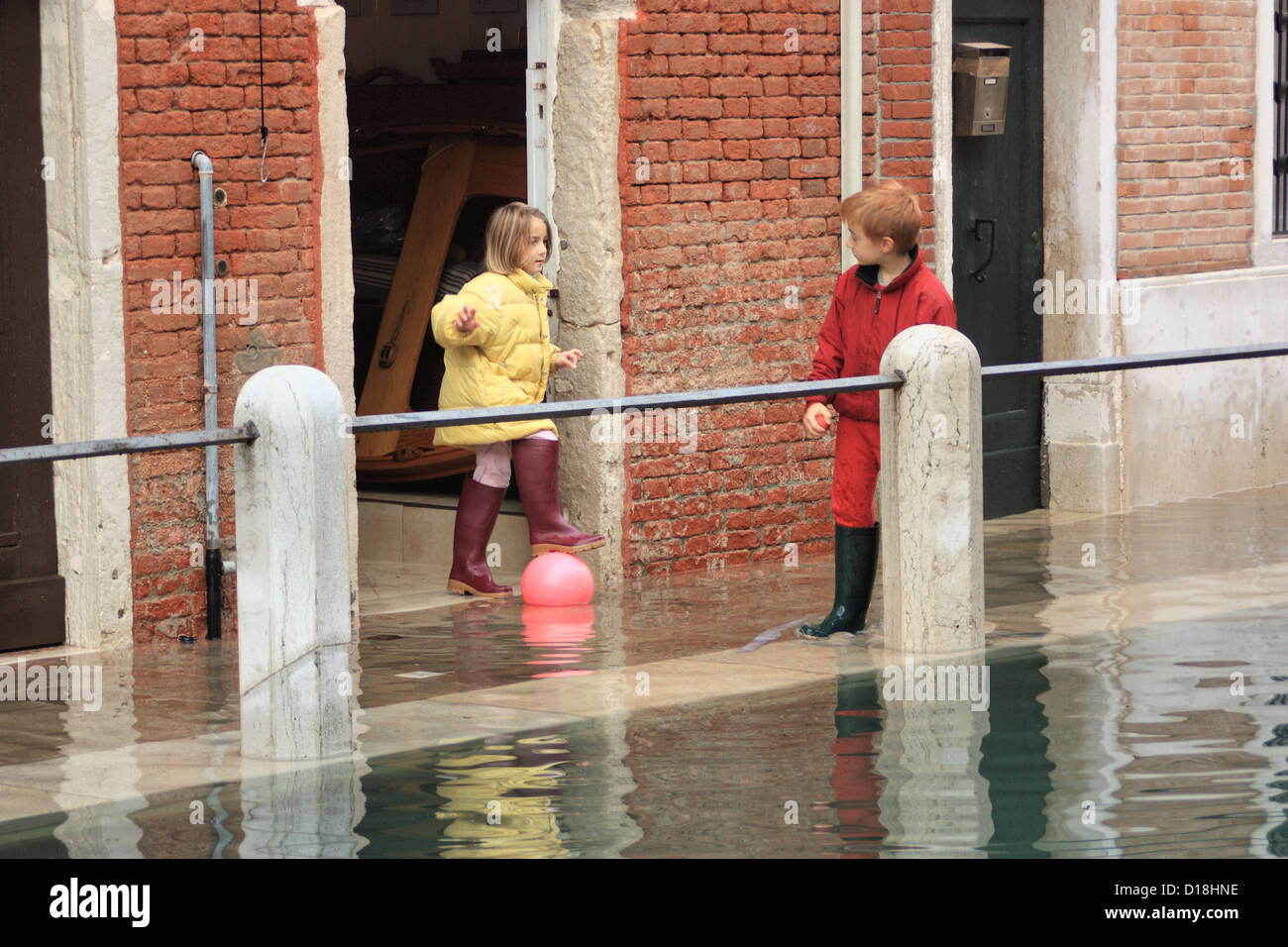 Bambini che giocano sulla strada durante "acqua alta" alluvione in Venezia. Foto Stock