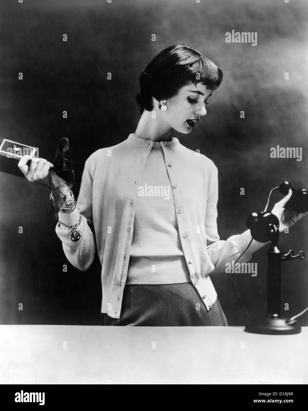 Maglione impostare degli anni cinquanta. Il 1955 foto di moda è in scena con un 1920s telefono per sottolineare i maglioni' atemporalità. Foto Stock