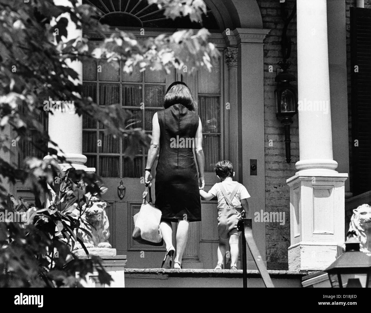 Jacqueline Kennedy e suo figlio, 3 anno vecchio John F Kennedy Jr. che entrano nel loro Georgetown era federale home. La casa è stata cianfrinata Foto Stock