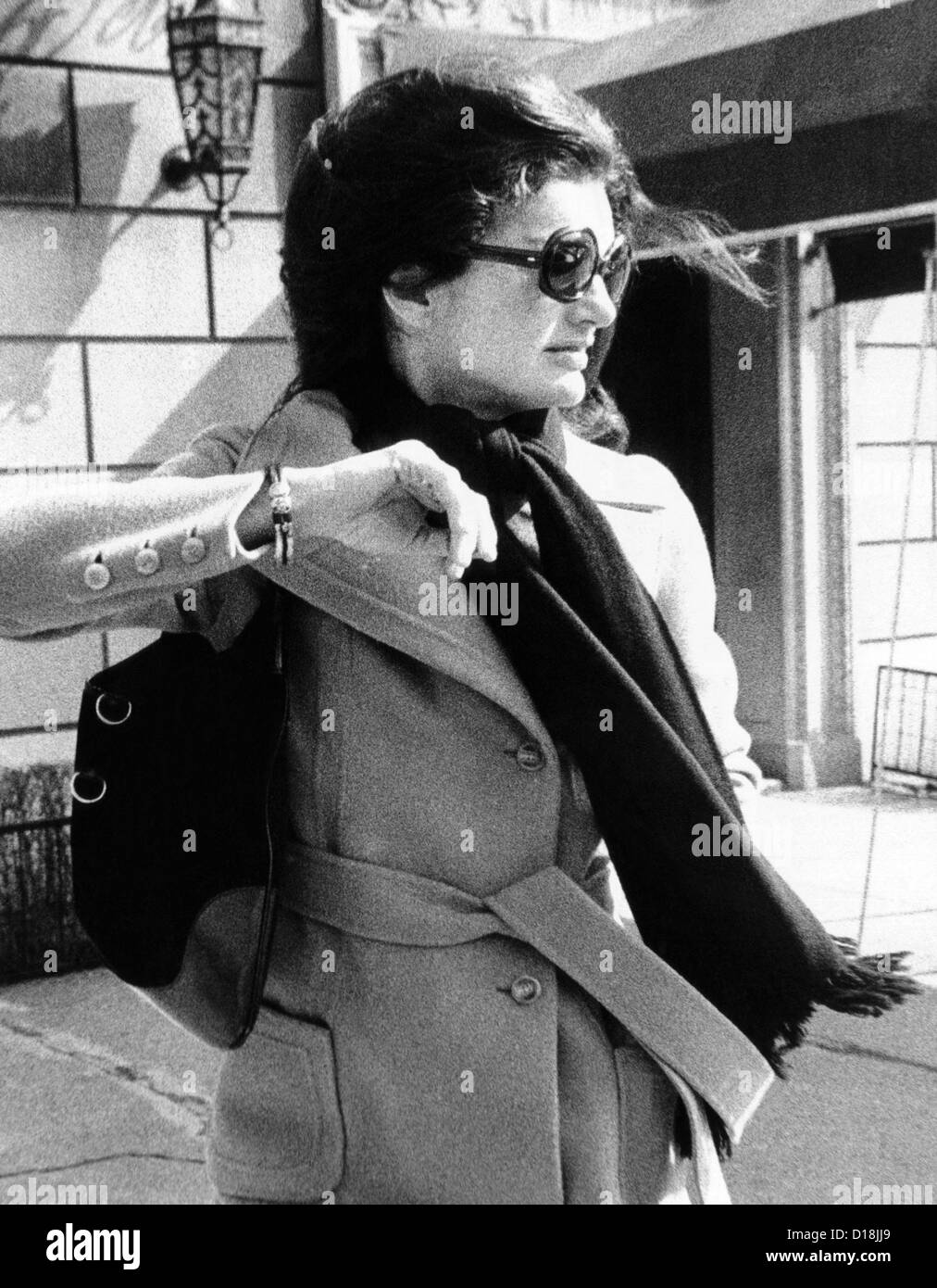 Jacqueline Kennedy Onassis, un vedovo di recente per una seconda volta, volge il capo e solleva il suo braccio per evitare un fotografo come Foto Stock
