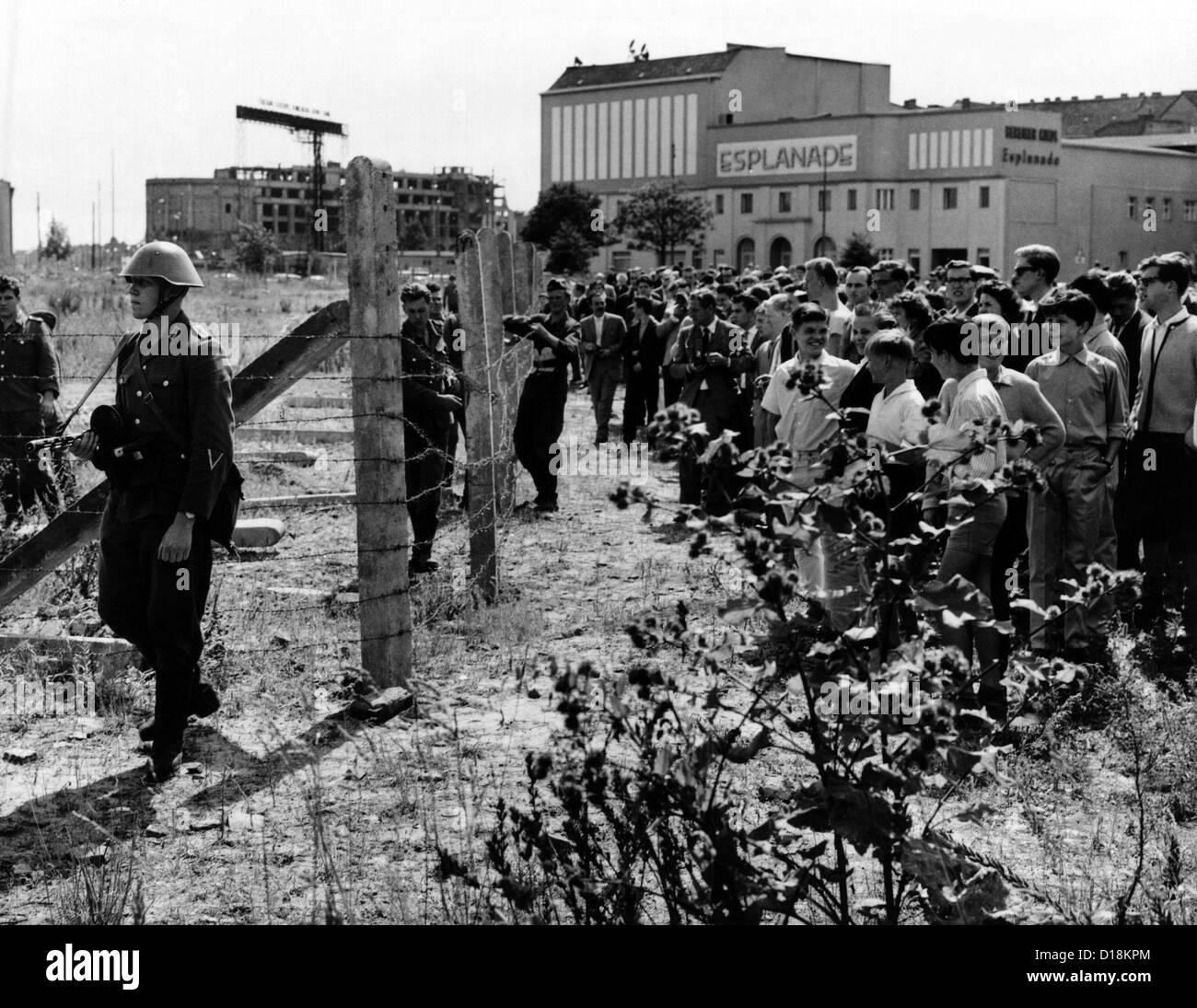 Primi giorni del muro di Berlino. West berlinesi est jeer soldati tedeschi pattugliano il nuovo filo spinato barricate per la chiusura Foto Stock