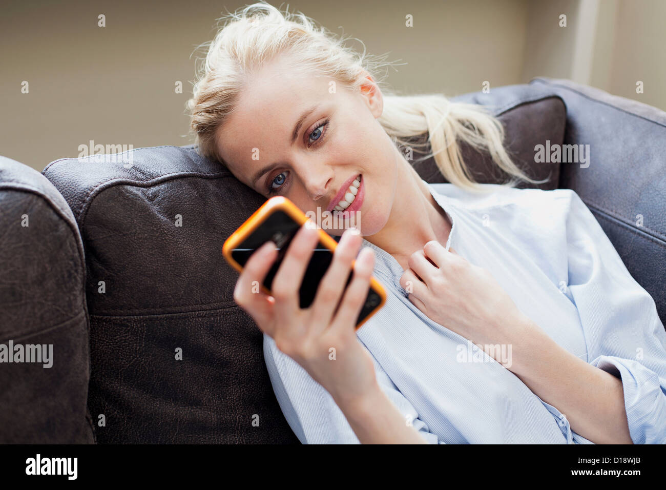Giovane donna guardando smartphone e sorridente Foto Stock