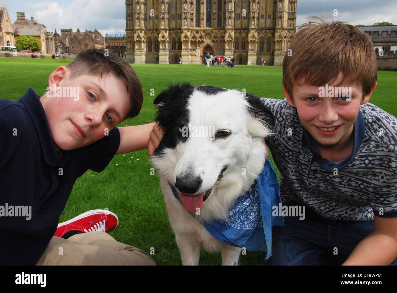 Due ragazzi e il loro cane nella parte anteriore della Cattedrale di Wells, Somerset REGNO UNITO Foto Stock