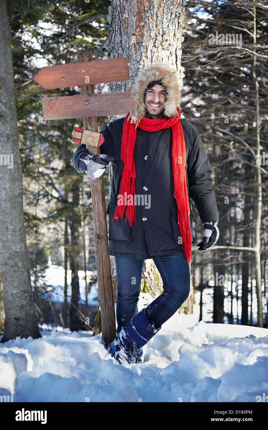 Uomo con cartello in legno in foresta Foto Stock