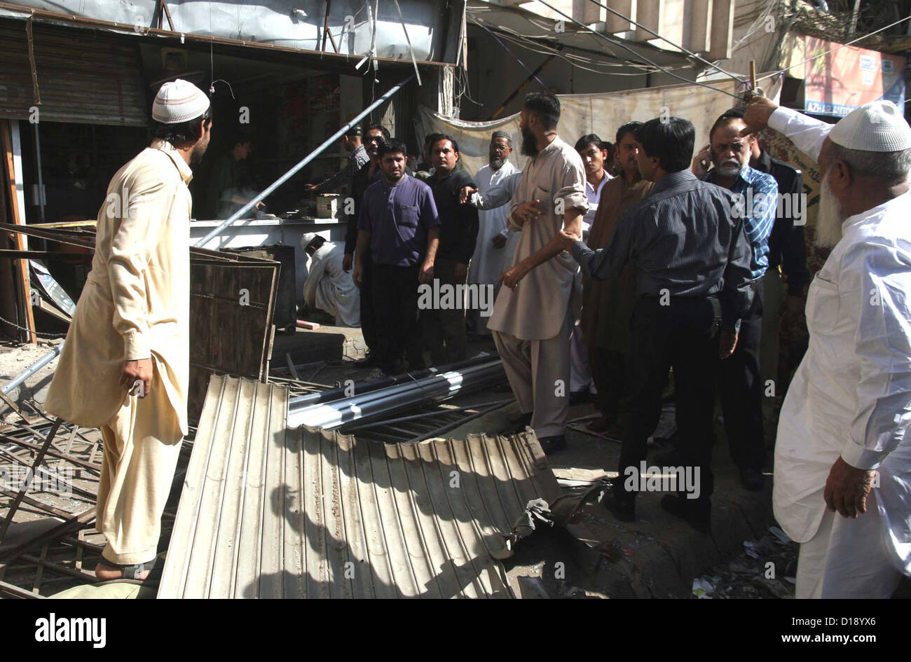 Le persone si radunano vicino shop dopo hand grenade attacco da estorsione mafia, durante una manifestazione di protesta al centro del Tibet a Karachi il Martedì, Dicembre 11, 2012. A Karachi in attività di estorsione mafia sono sul picco, essi rendono molestare la business class dal procedere a tale tipo di attività distruttiva e la domanda di denaro. Foto Stock