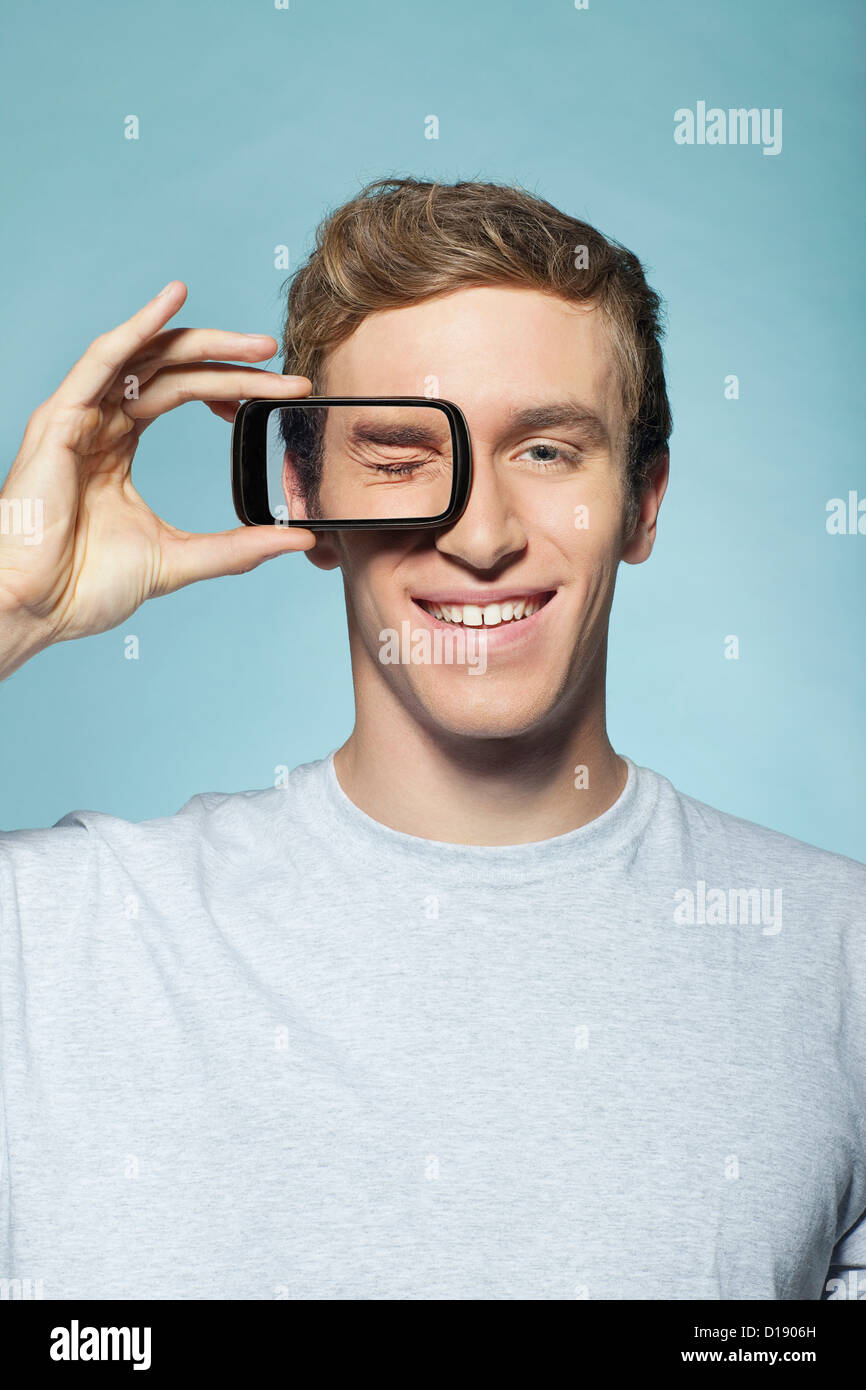 Uomo con smartphone over eye Foto Stock