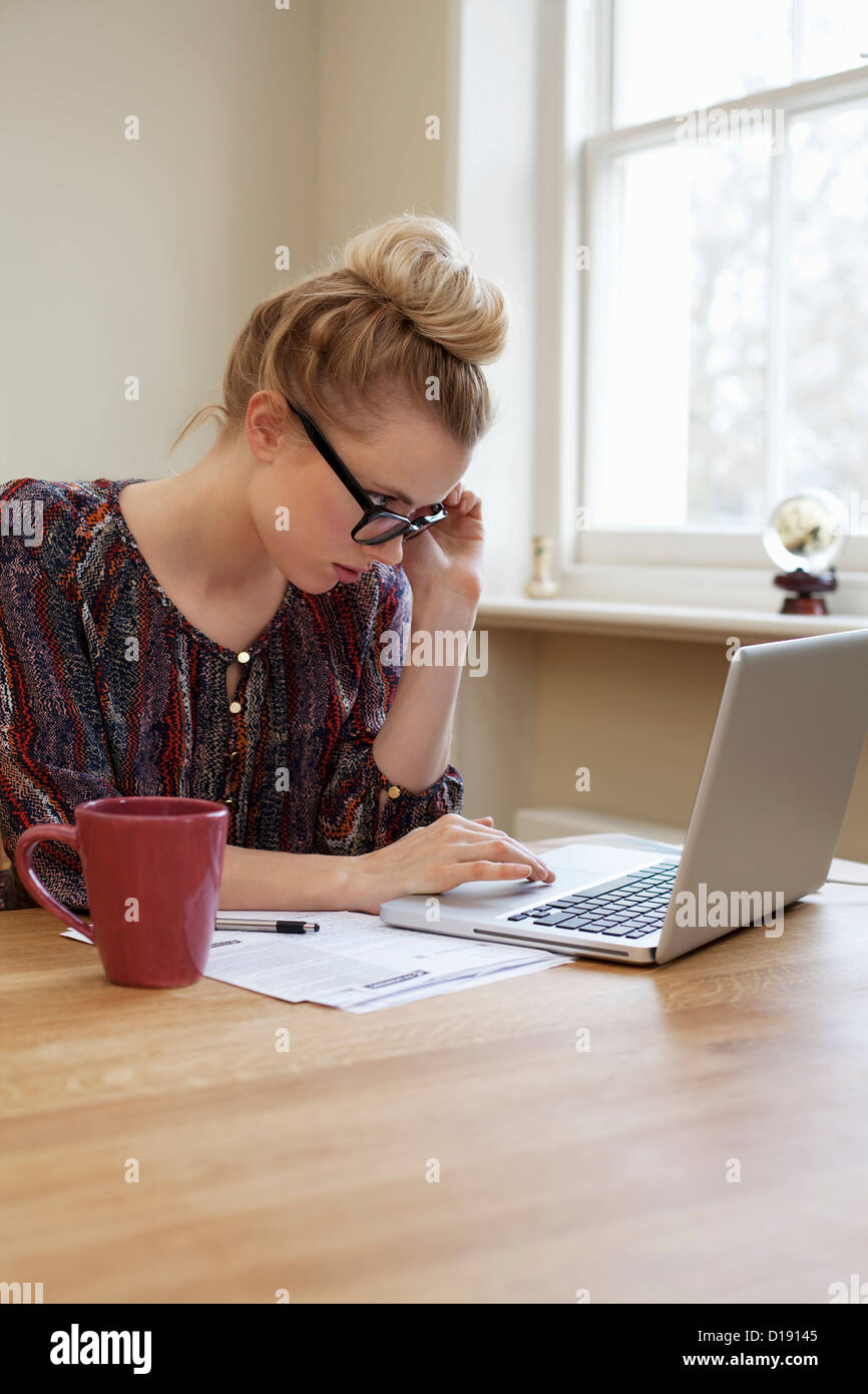 Giovane donna che indossa gli occhiali, utilizzando laptop Foto Stock