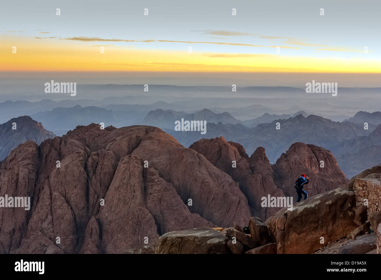 Un individuo orologi sunrise dal bordo di una scogliera sulla sommità del monte Sinai nel deserto del Sinai Foto Stock