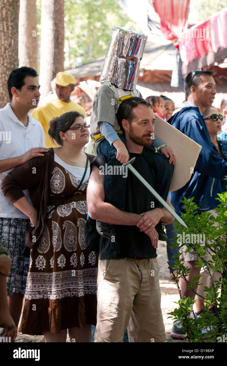 Un uomo con il suo figlio sulle spalle vestito come un cavaliere con la folla dietro la visione di spettacolo presso il Maryland Renaissance Festival 2012. Foto Stock