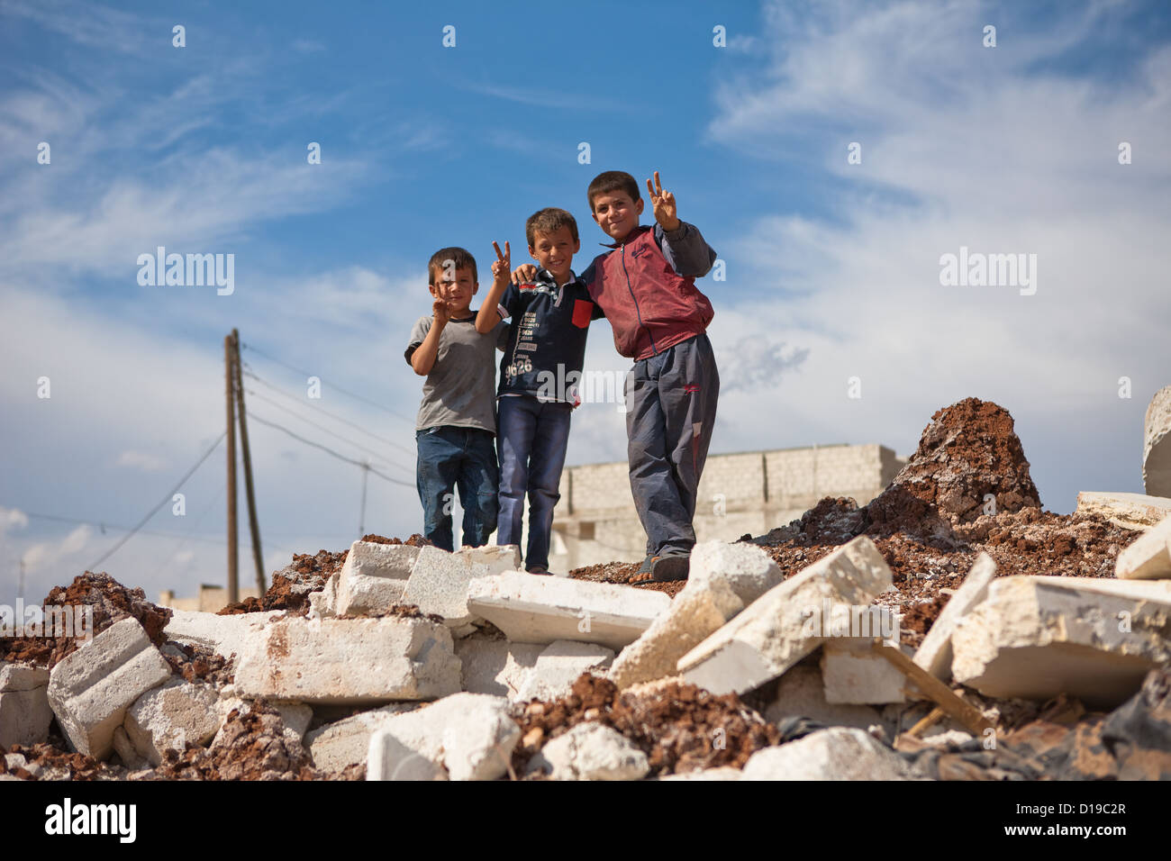 Azaz, Siria, 5/10/12. Bambini stand sulla cima di macerie da una forma ripiegata house. Foto Stock