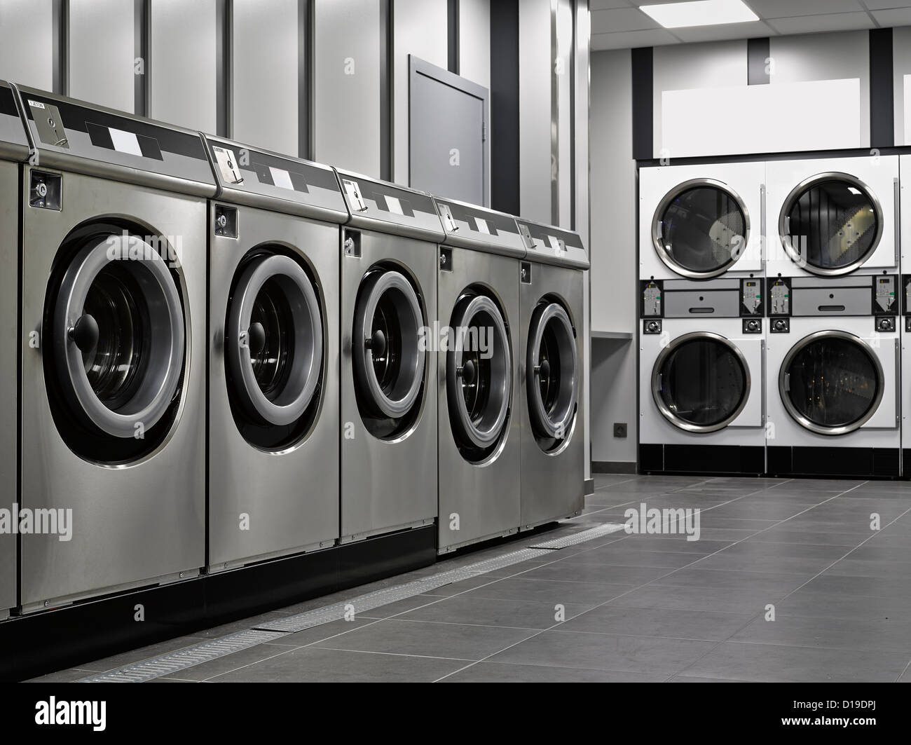 Una fila di macchine lavatrici industriali in una lavanderia pubblica Foto Stock